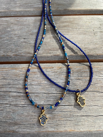 Blue micro pave hamsa charm on blue beaded necklace.